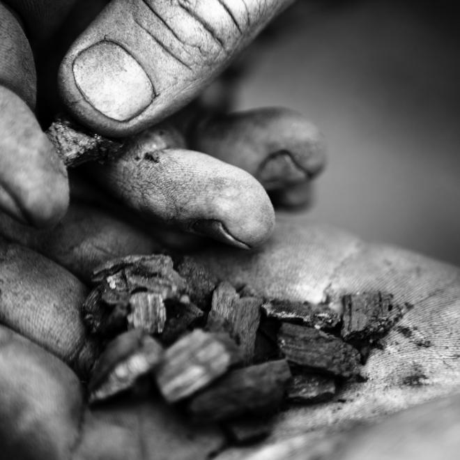 Black and white image of biochar in a man's hands.