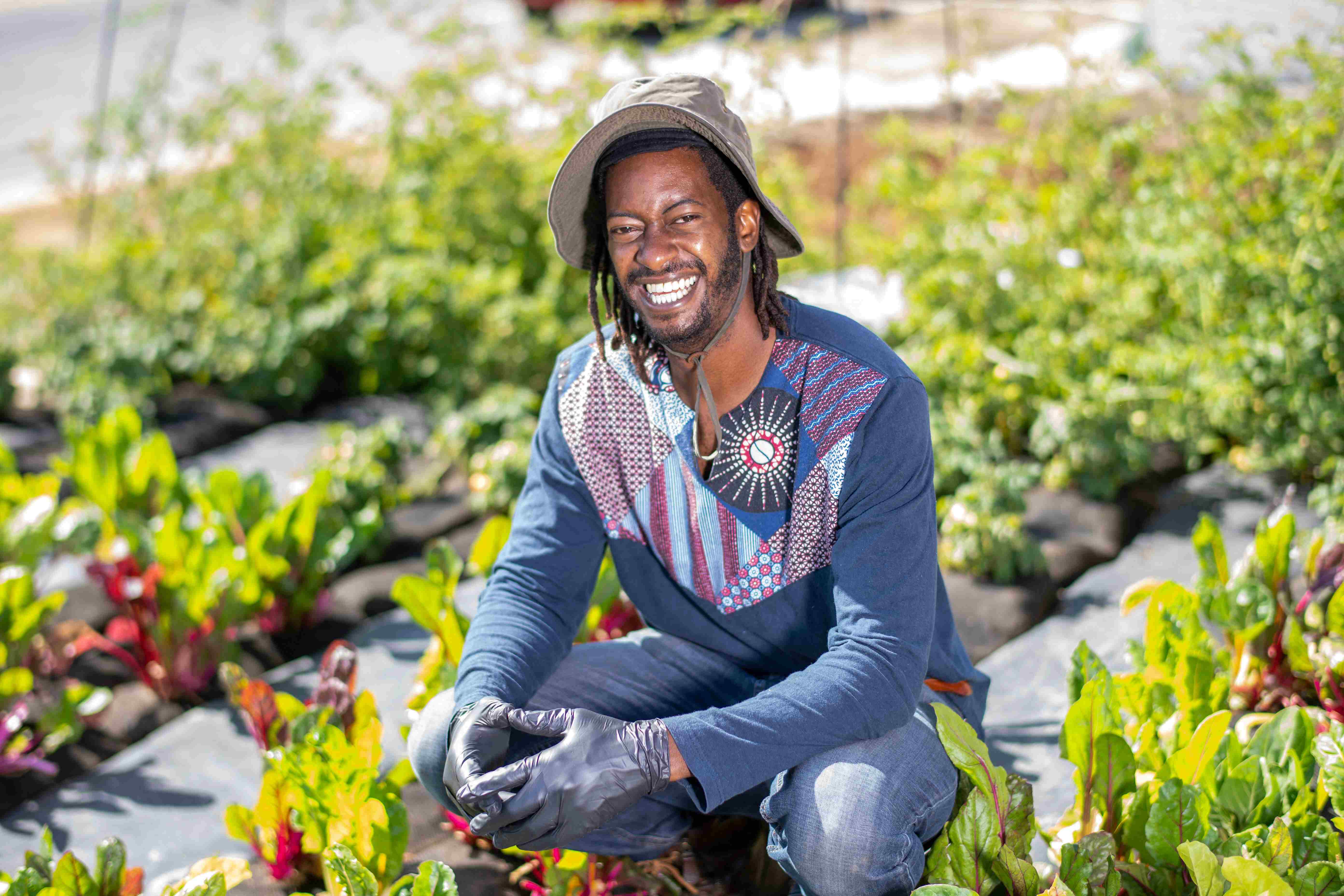 Crop Swap LA founder Jamiah Hargins poses in the middle of the crops at the Asante Microfarm in Los Angeles, California.