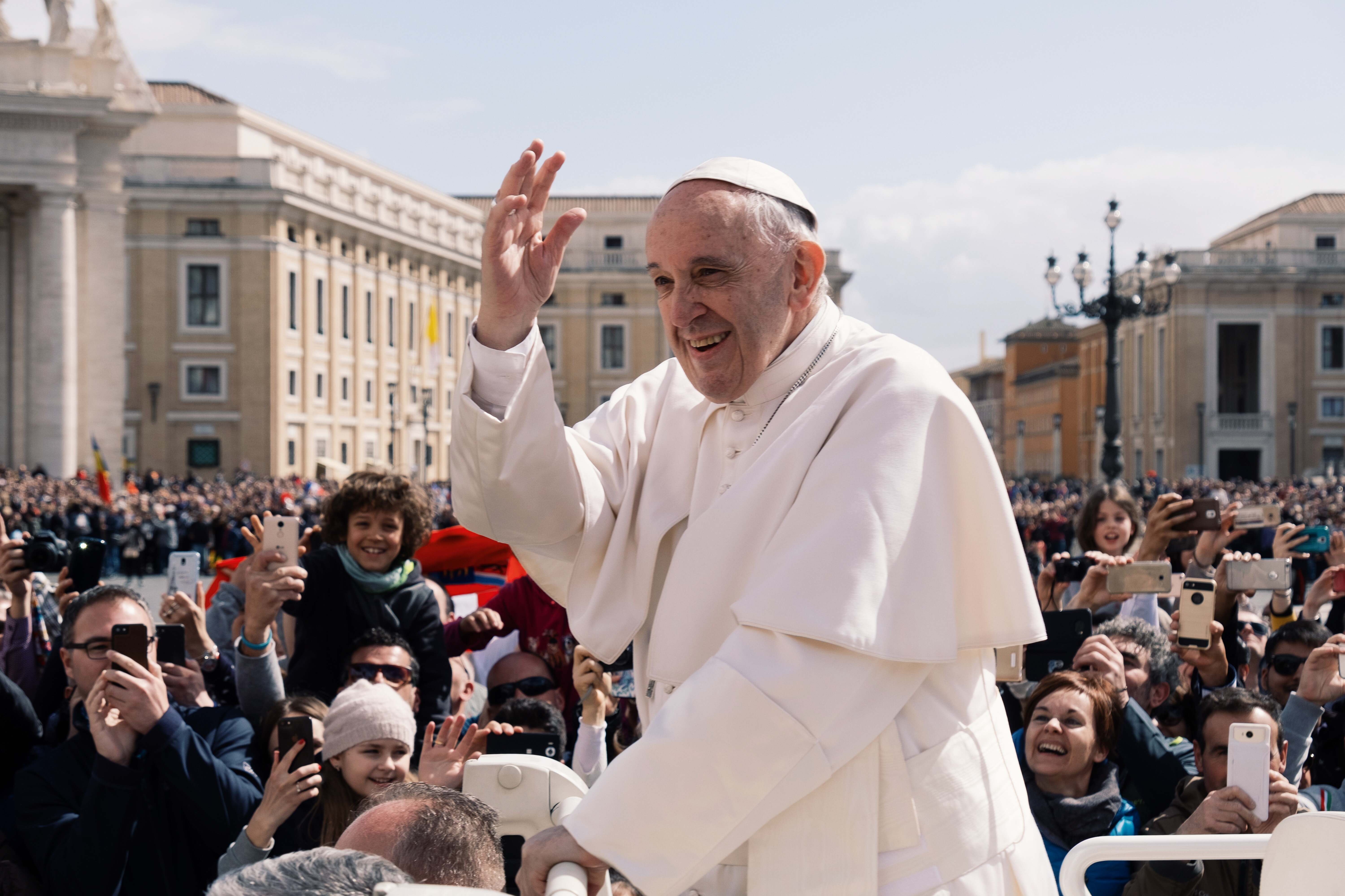 Pope Francis waving at a crowd at the Vatican. 