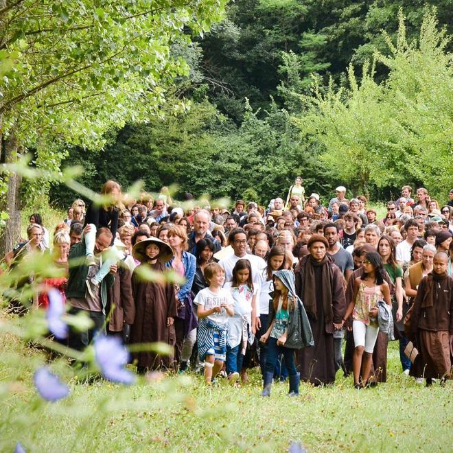 Zen master Thich Nhat Hanh walking with a large group in nature.