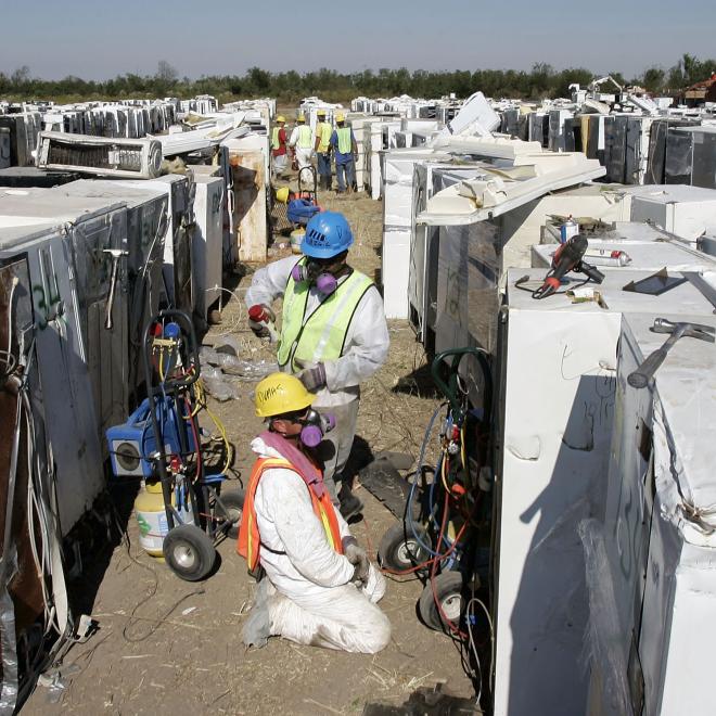 EPA workers prepare to remove freon, compressor oil, mercury switches, and rotten food from refrigerators and other "white goods" at the Katrina Dumpsite on October 19, 2005, in New Orleans, Louisiana.