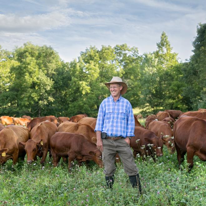Regenerative rancher Greg Judy smiling with his cattle on pasture.
