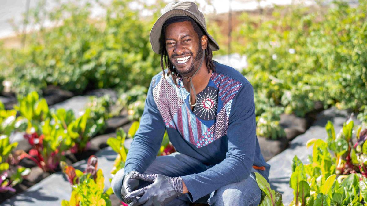 Crop Swap LA founder Jamiah Hargins poses in the middle of the crops at the Asante Microfarm in Los Angeles, California.