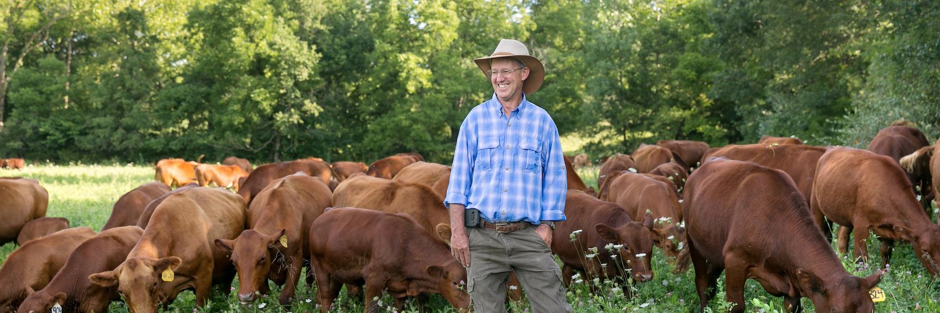 Regenerative rancher Greg Judy smiling with his cattle on pasture.
