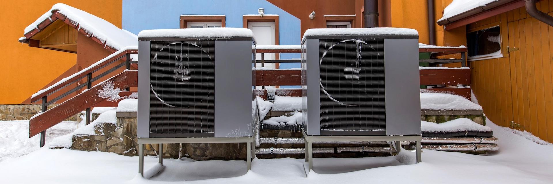 Two residential modern heat pumps buried in snow.